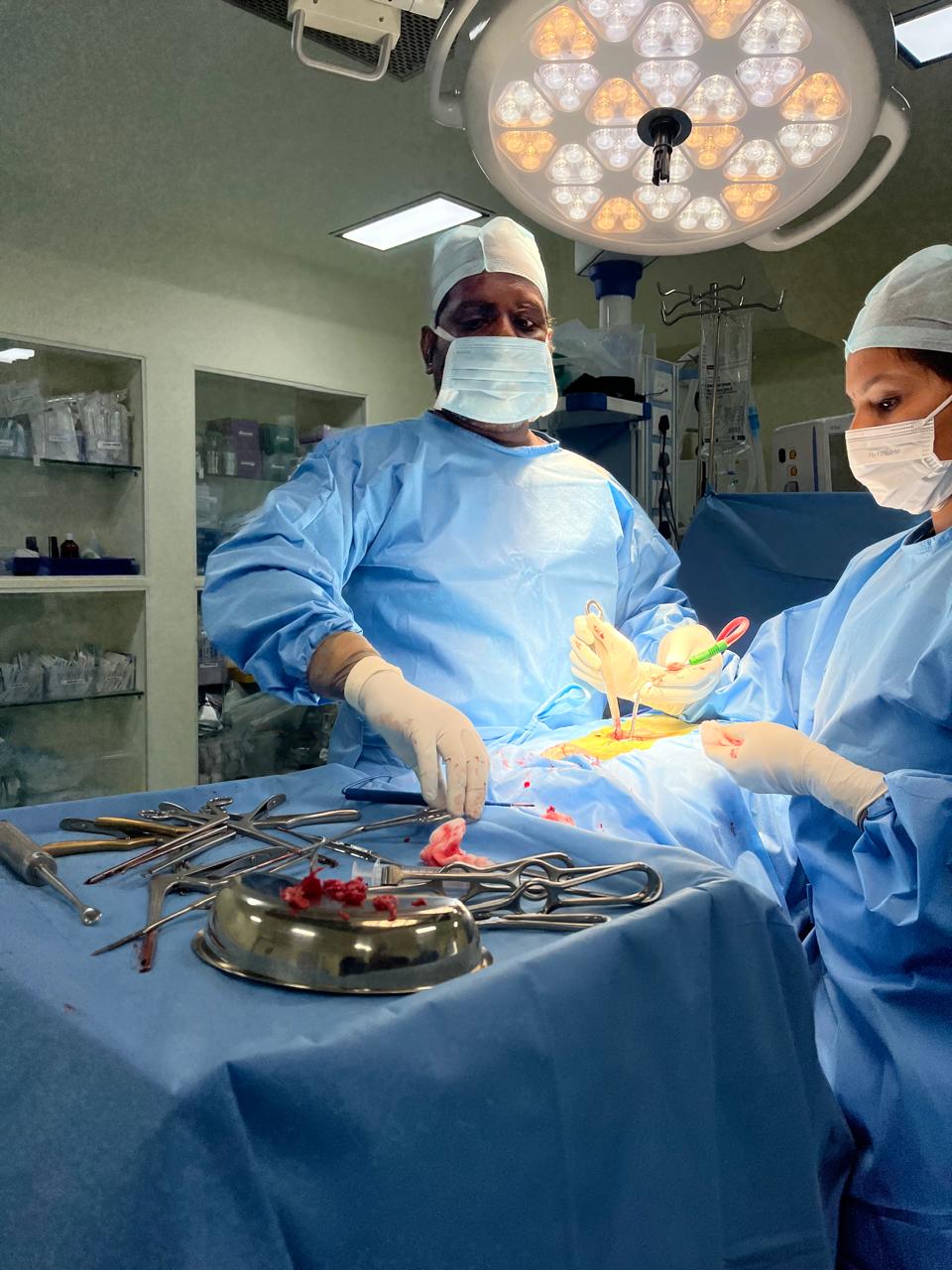 Surgeons operating in a well-lit surgical room with tools on a tray